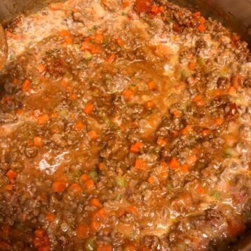 Bolognese sauce simmering in a large skillet