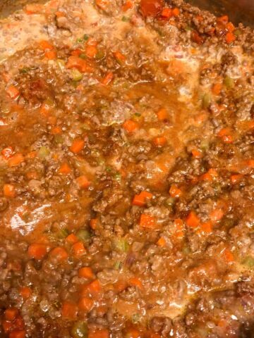 Bolognese sauce simmering in a large skillet