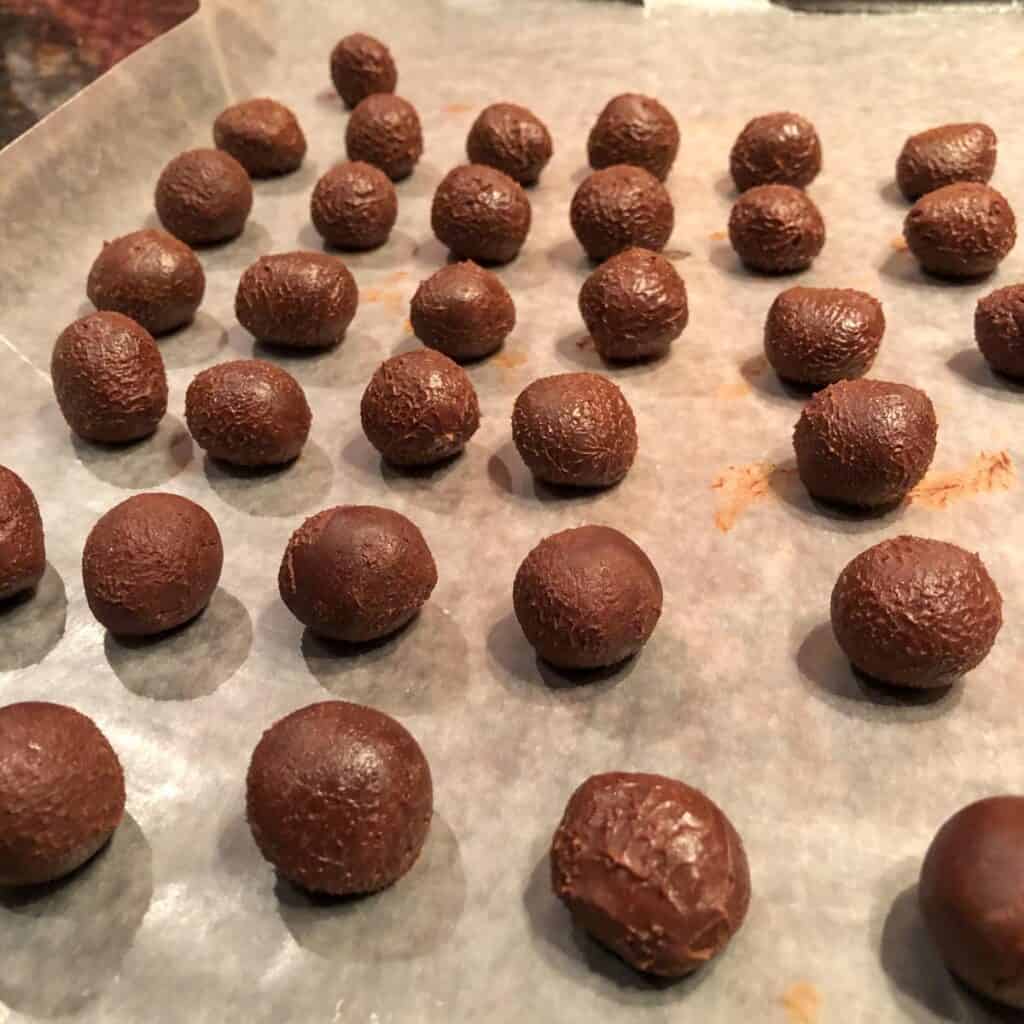 hand rolled chocolate truffles on parchment paper waiting for covered garnish.