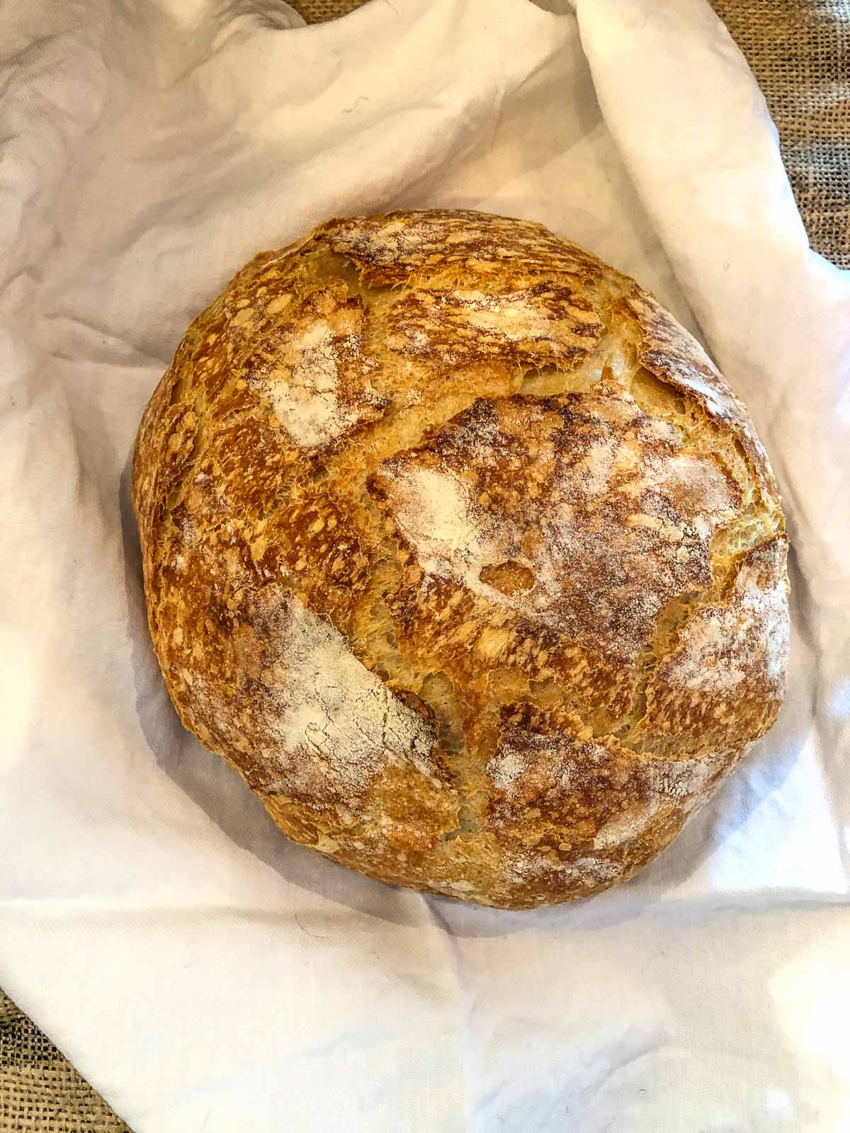 a fresh baked loaf of sourdough bread on a white napkin.